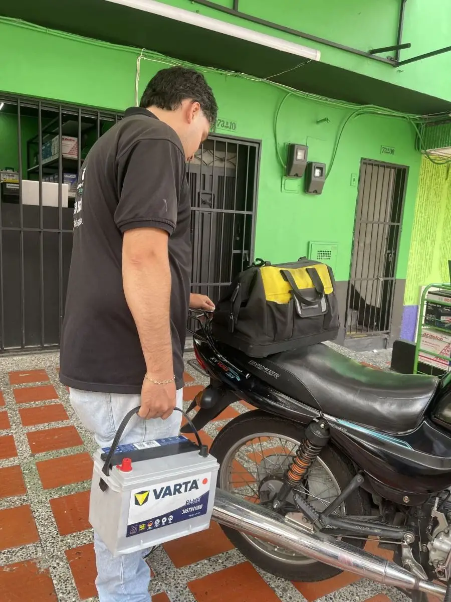 Técnico saliendo en moto con una batería nueva